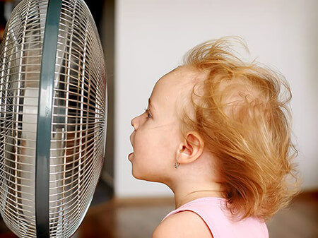 Girl sitting in front of fan in need of AC in NC